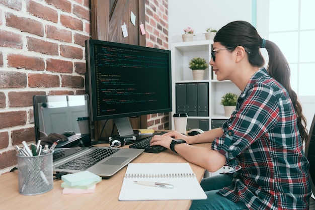 programmatore femminile sorridente di bellezza che utilizza il computer che lavora in ufficio e digita il codice dati per lo sviluppo di un nuovo sistema di protezione della sicurezza degli utenti online.