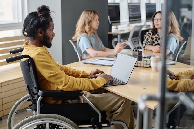 Programmatore maschio con disabilità che lavora sul suo computer portatile in ufficio