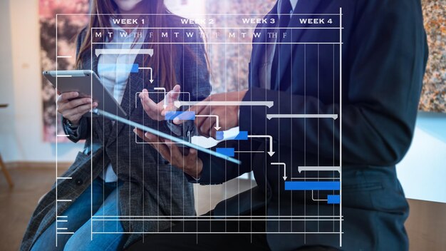 Project manager che lavora e aggiorna le attività con le pietre miliari pianificazione dello stato di avanzamento e diagramma di pianificazione del diagramma di Gantt business lavorando con smartphone tablet e laptop in officexA