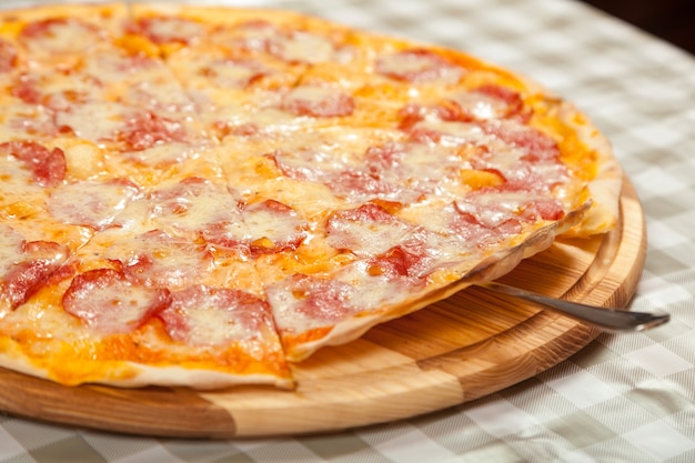 Pronta pizza sottile e deliziosa sul tavolo in un caffè. Cucinare la pizza in pizzeria.