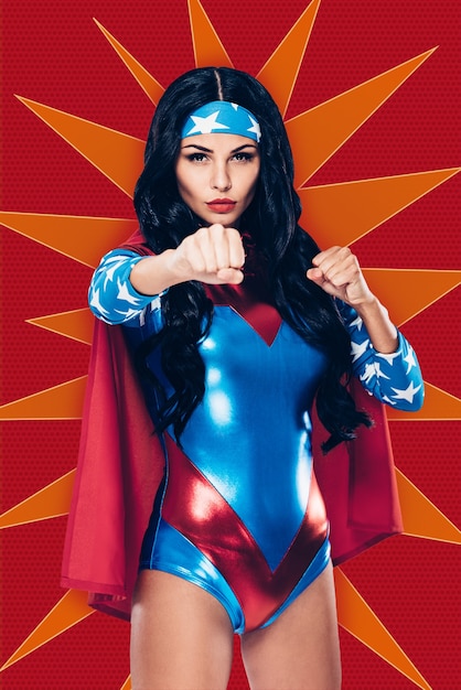 pronto a combattere il crimine. bella giovane donna in costume da supereroe guardando la telecamera e tenendo i pugni