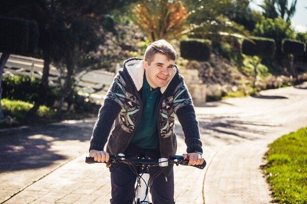 Pronto a guidare. Bel giovane in bicicletta che guarda l'obbiettivo e sorride mentre in piedi all'aperto.