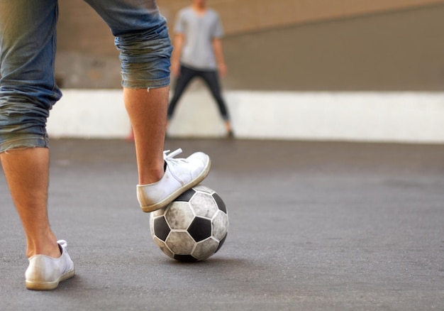 Pronto a segnare Immagine ritagliata del piede di un uomo su un pallone da calcio in strada