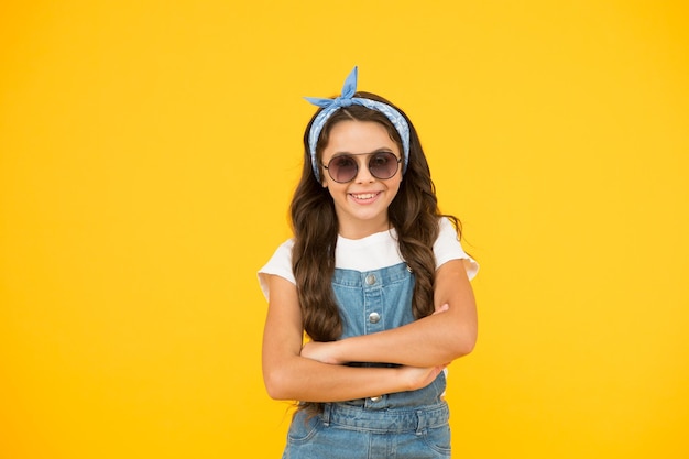 Pronto per il tempo soleggiato Concetto di moda estiva bambina allegra sfondo giallo capretto retrò capelli lunghi capretto piccolo occhiali da sole vintage Modalità vacanza su piccola fashionista Boutique di abbigliamento per bambini