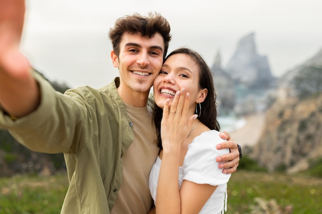 Proposta indimenticabile sulla coppia felice sulla spiaggia che abbraccia e scatta selfie dopo il fidanzamento