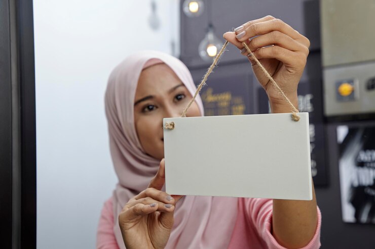 Foto proprietaria che indossa l'hijab mentre tiene un cartello nel negozio