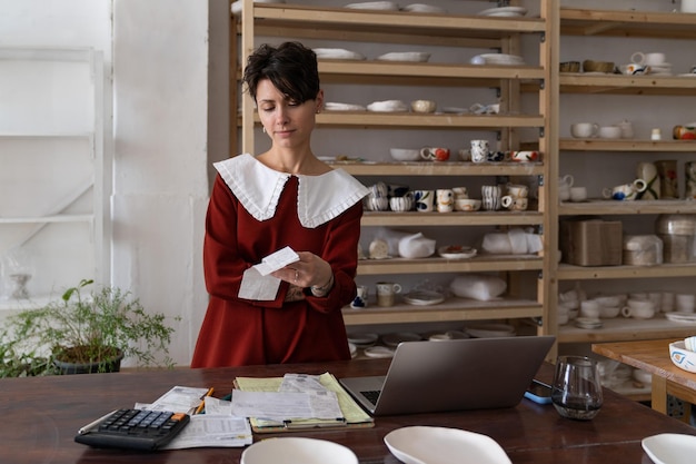 Proprietario di un negozio di ceramiche femminile che guarda il conto pensando a come rendere il business più redditizio