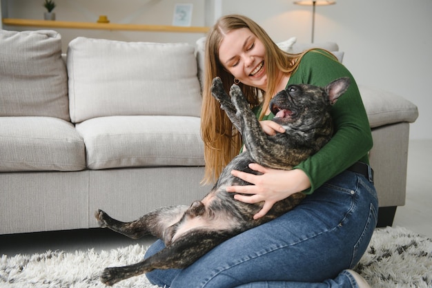 Proprietario femminile che gioca con un cane gioioso a casa Giocando con il concetto di cane