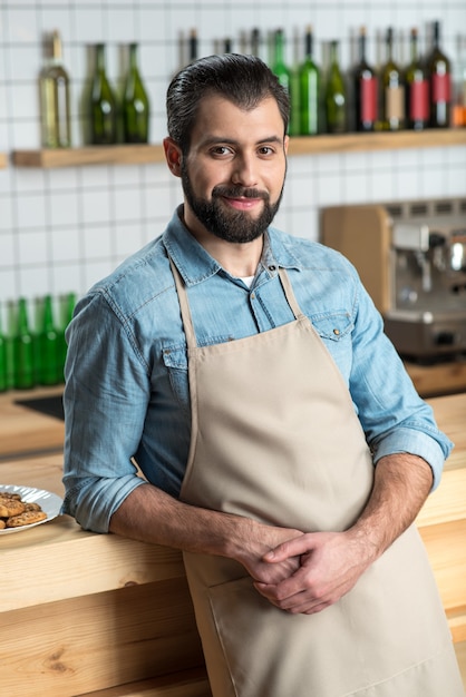 Proprietario intelligente. Allegro proprietario creativo intelligente di un nuovo e confortevole bellissimo caffè appoggiato al bancone del bar in legno e sorridente mentre aspetta che arrivino i camerieri