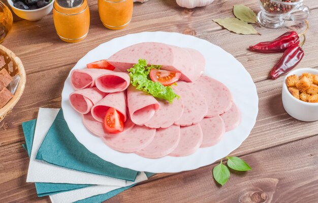 Prosciutto affettato su un piatto bianco su un fondo di legno.