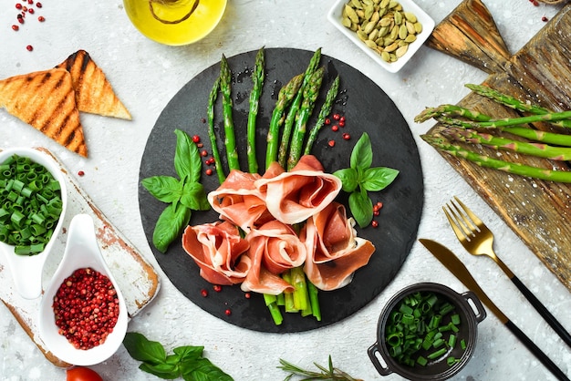 Prosciutto con asparagi e basilico Su un piatto di pietra nera Top