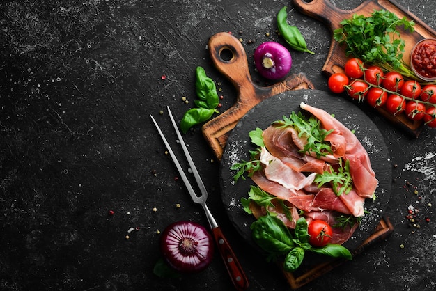 Prosciutto con rucola e basilico su un piatto nero Cucina spagnola Vista dall'alto Spazio libero per il testo