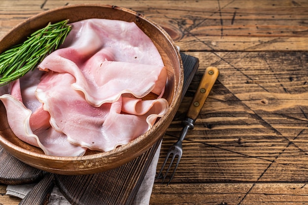 Prosciutto crudo affettato in un piatto di legno. fondo di legno. Vista dall'alto. Copia spazio.