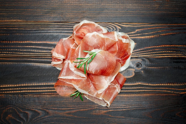 Prosciutto crudo italiano o prosciutto spagnolo. Prosciutto crudo su superficie di legno