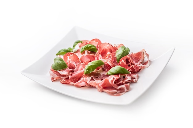 Prosciutto. Fette arricciate di delizioso prosciutto italiano con basilico.