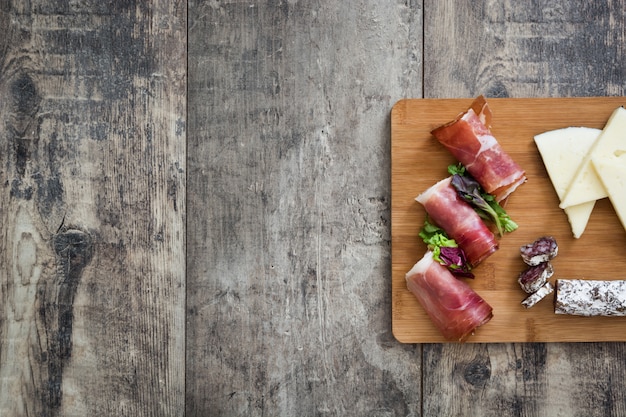 Prosciutto serrano spagnolo, formaggio e salsiccia su una tavola di legno rustica copia spazio