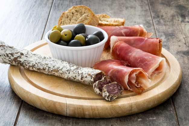 Prosciutto serrano spagnolo, olive e salsicce su legno