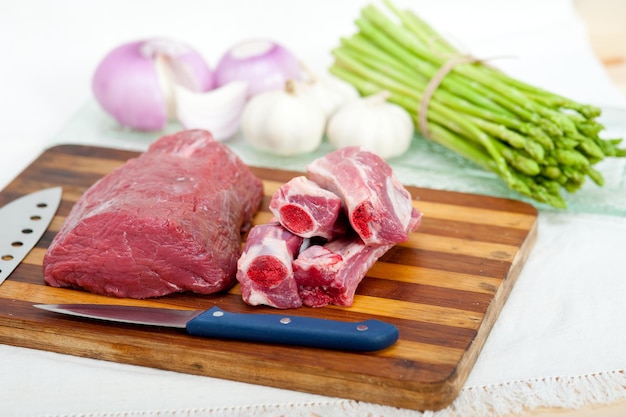 Prossimo piano di carne di manzo sul tavolino da taglio con verdure sulla tavola