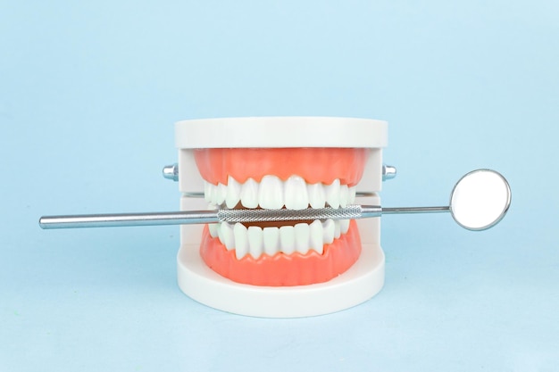 Protesi dentale con specchio della bocca del dentista su sfondo blu primo piano Mascella dei denti di vecchiaia