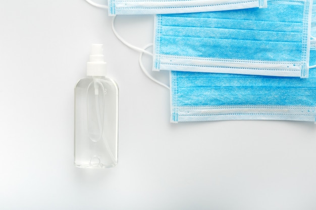 Protezione dal coronavirus. Bottiglia di disinfettante per le mani e maschere chirurgiche protettive mediche sul tavolo bianco.