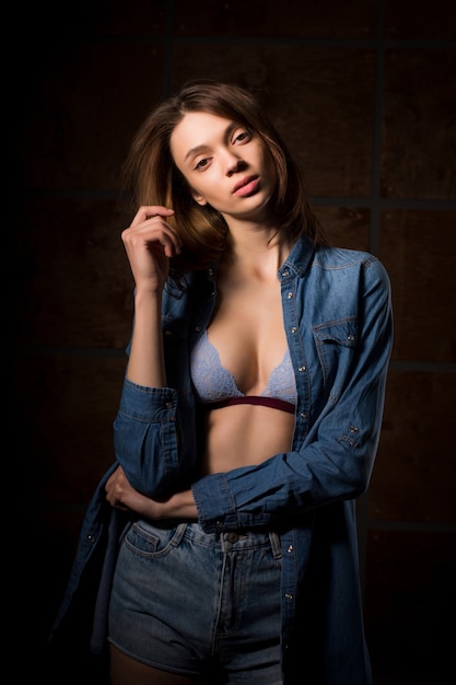 Prova il servizio fotografico per una giovane adorabile donna bruna che indossa una camicia di jeans