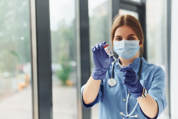 Provetta con vaccino La giovane dottoressa in uniforme è al chiuso