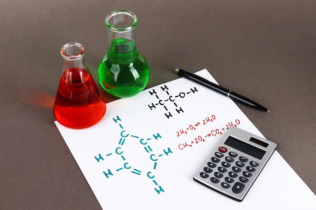 Provette con liquidi colorati e formule su sfondo grigio