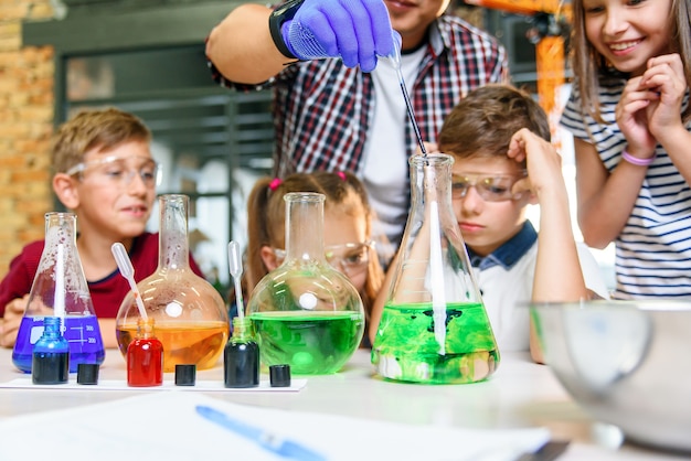 Provette con sostanze liquide colorate. Studio degli stati liquidi. Gli alunni delle scuole di gruppo con provette studiano liquidi chimici. Concetto di scienza. Ragazze e ragazzi forniscono esperimenti con liquidi.