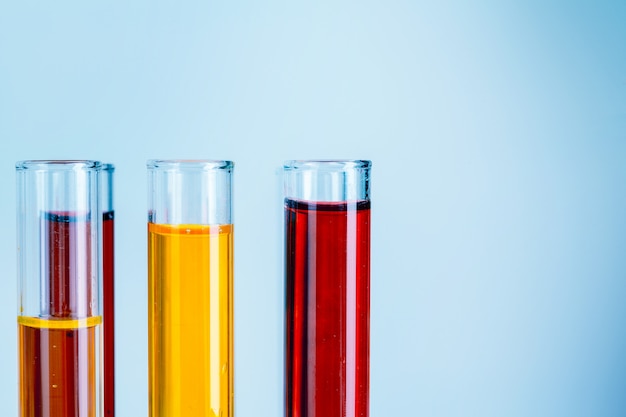 Provette di laboratorio con liquidi rossi e gialli su sfondo azzurro