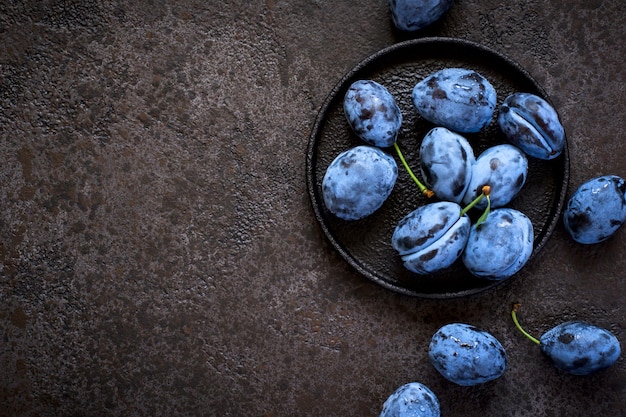 Prugne blu scuro in lastra di ghisa su sfondo nero.