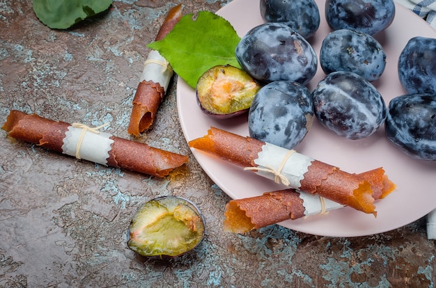 Prugne fresche raccolte in un piatto di ceramica e pastiglie di prugne