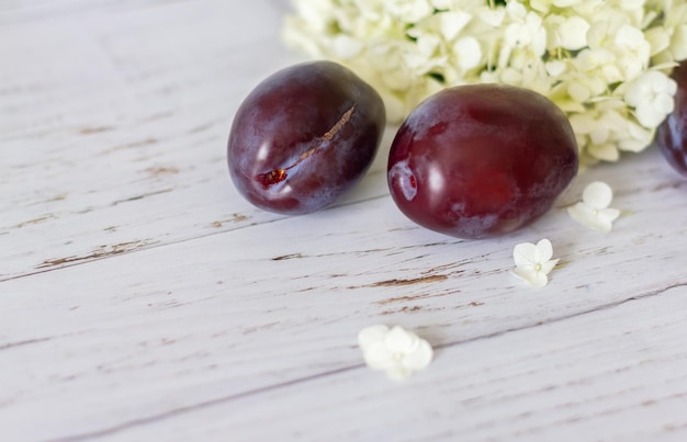 Prugne mature su uno sfondo di legno fiori di ortensia si trovano nelle vicinanze