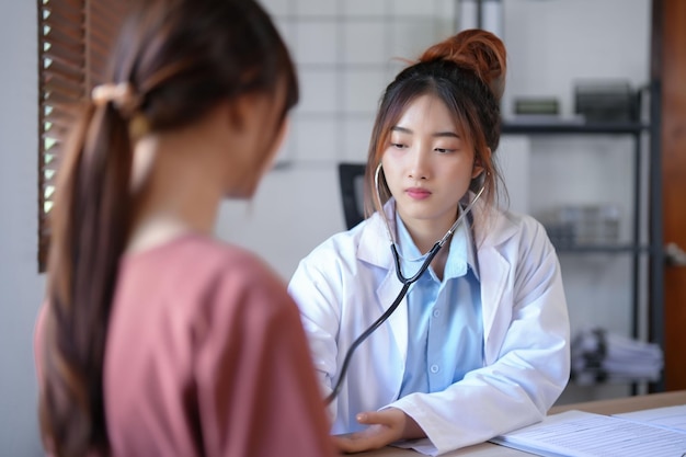 Psicologa asiatica donne che ascoltano il battito cardiaco del paziente con lo stetoscopio e danno consulenza sulla terapia della salute mentale mentre la paziente donna soffre di stress e ansia con problemi di salute psicologica