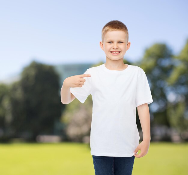 pubblicità, estate, persone e concetto di infanzia - ragazzo sorridente in t-shirt bianca vuota che punta il dito su se stesso sullo sfondo del parco