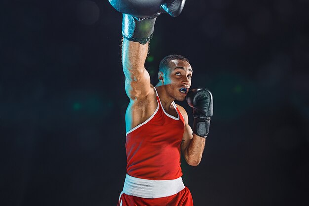 Pugile maschio afroamericano. Allenamento di boxe del giovane in un fitness club. Uomo forte muscolare su sfondo nero studio