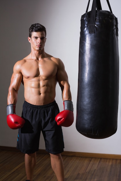 Pugile muscolare con sacco da boxe in palestra