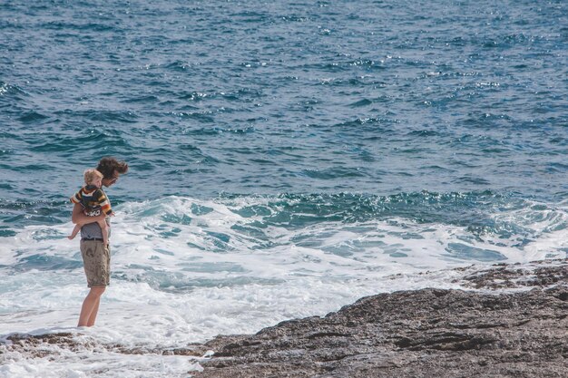 PULA CROAZIA 20 maggio 2019 giovane padre che tiene il bambino sulle mani che mostra le onde in mare