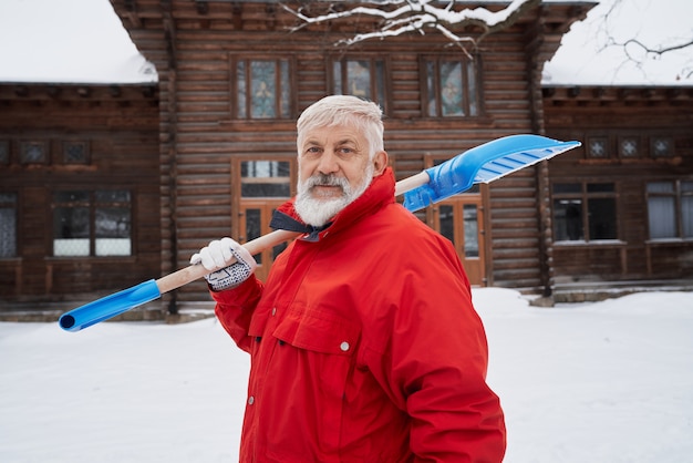 Pulitore con pala da neve sulla spalla.