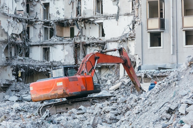 Pulizia dei detriti di costruzione con una benna di un escavatore rovine dell'edificio