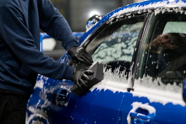 Pulizia e lavaggio di un'auto pulendo la carrozzeria con schiuma e spugna