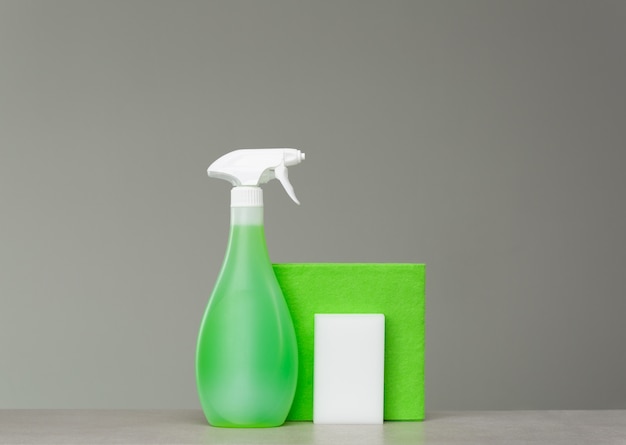 Pulizia flacone spray verde con dispenser in plastica, spugna e panno per polvere su grigio