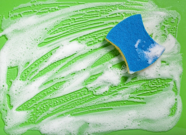 Pulizia spugna tergi schiuma sapone schiuma su sfondo verde concetto di lavaggio domestico