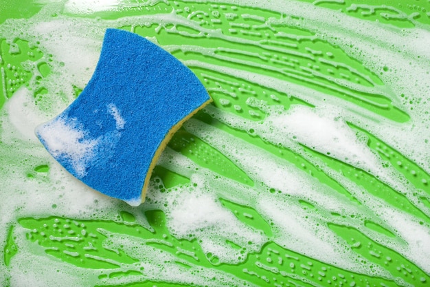 Pulizia spugna tergi schiuma sapone schiuma su sfondo verde concetto di lavaggio domestico