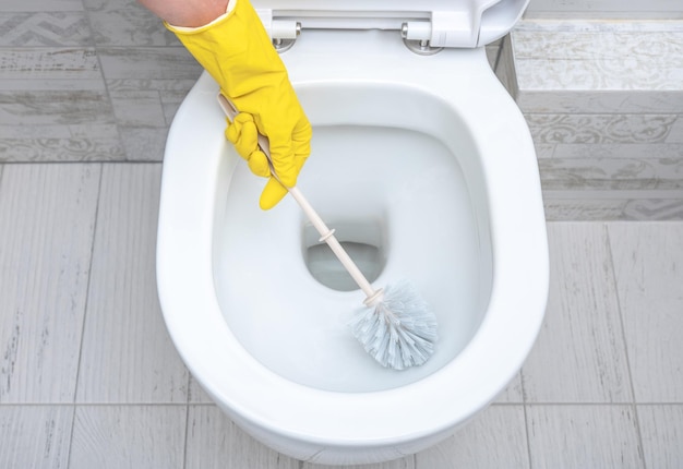 Pulizia wc Governante che pulisce l'uomo al gabinetto Spazzolare i servizi igienici per la pulizia e l'igiene Pulizia del water Concetto di servizio di pulizia