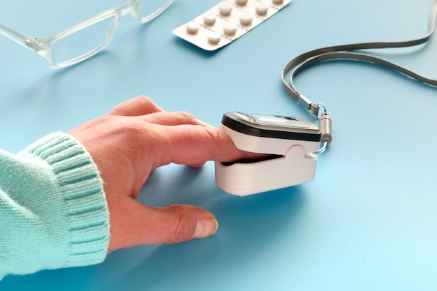Pulsossimetro, dispositivo digitale a dito per misurare la saturazione di ossigeno della persona. Ossigenazione ridotta: segno di emergenza di polmonite causata da influenza o nuovo coronavirus. Dispositivo sulla mano femminile caucasica.