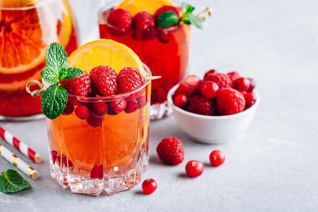 Punch alla sangria al mirtillo e lampone o Mojito in bicchieri con fettine d'arancia e menta