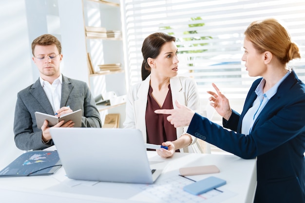 Punto acuto. Tre colleghi professionisti ambiziosi hanno litigato e una donna gesticola mentre spiega la sua idea