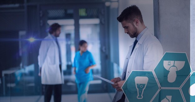 Punto di luce e più icone mediche contro il medico maschio utilizzando la tavoletta digitale in ospedale