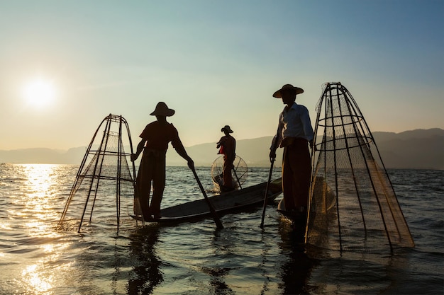 Punto di riferimento dell'attrazione di viaggio del Myanmar tre pescatori birmani tradizionali al lago Inle Myanmar famosi per il loro caratteristico stile di canottaggio a una gamba