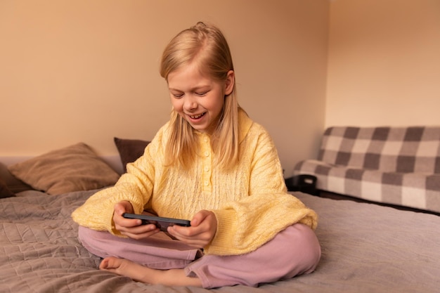 Punto di vista completo della piccola ragazza sveglia che sorride al telefono